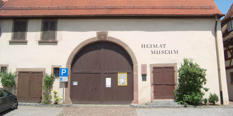  Auf dem Gebäude steht rechts "Heimat Museum", darunter ist eine Tür, in der Mitte ist ein großes Eingangstor 